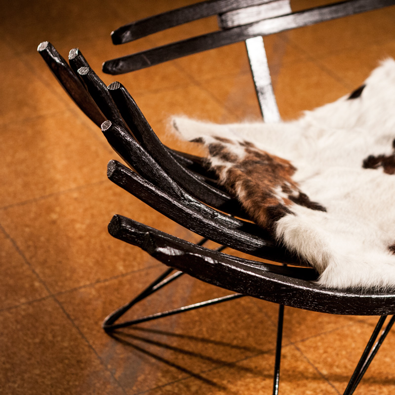 A close-up of the burnt and bent timbers of the Carbon Chair, you can also see the cowskin cushion