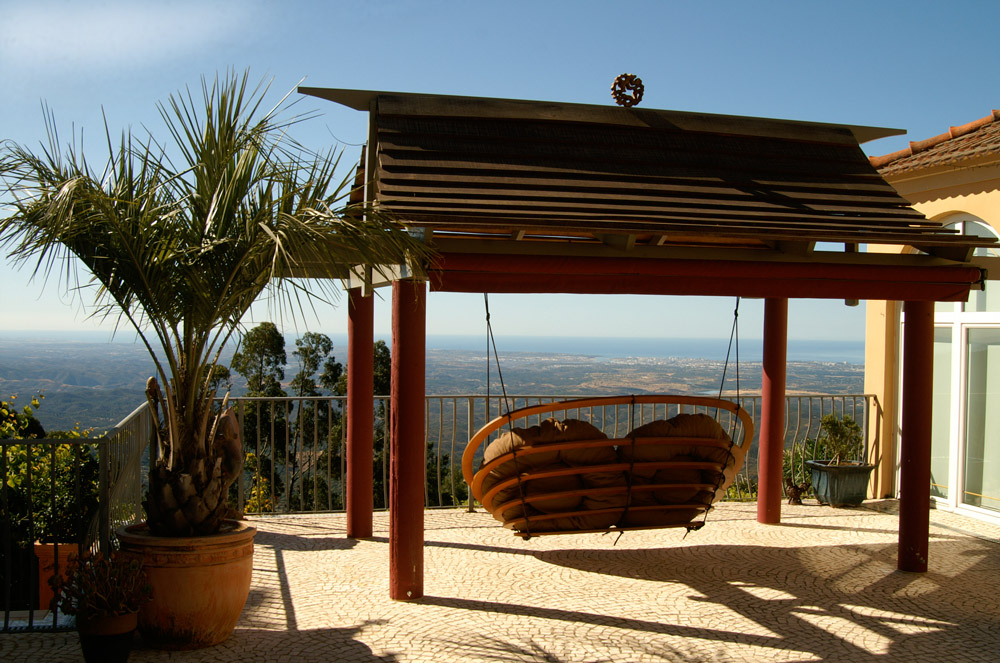 A Circa double hanging outdoors in the garden of a house on a hill, in an exotic location with a breath-taking view